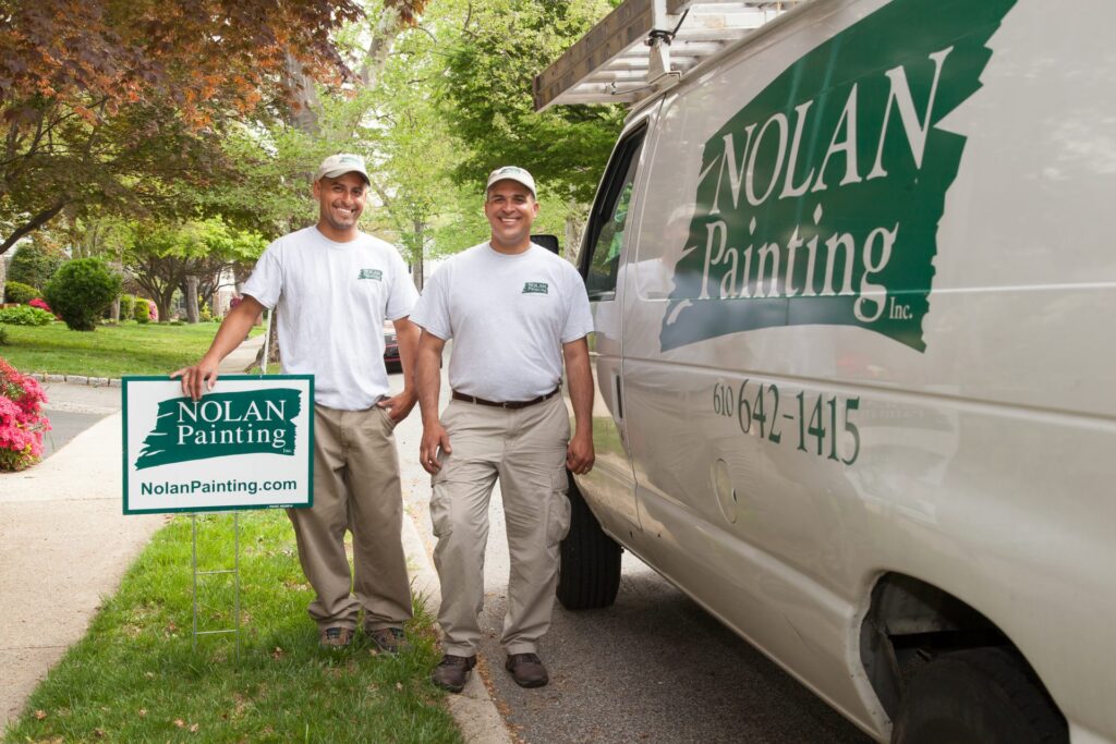 Two employees in front of Nolan Sign and Van