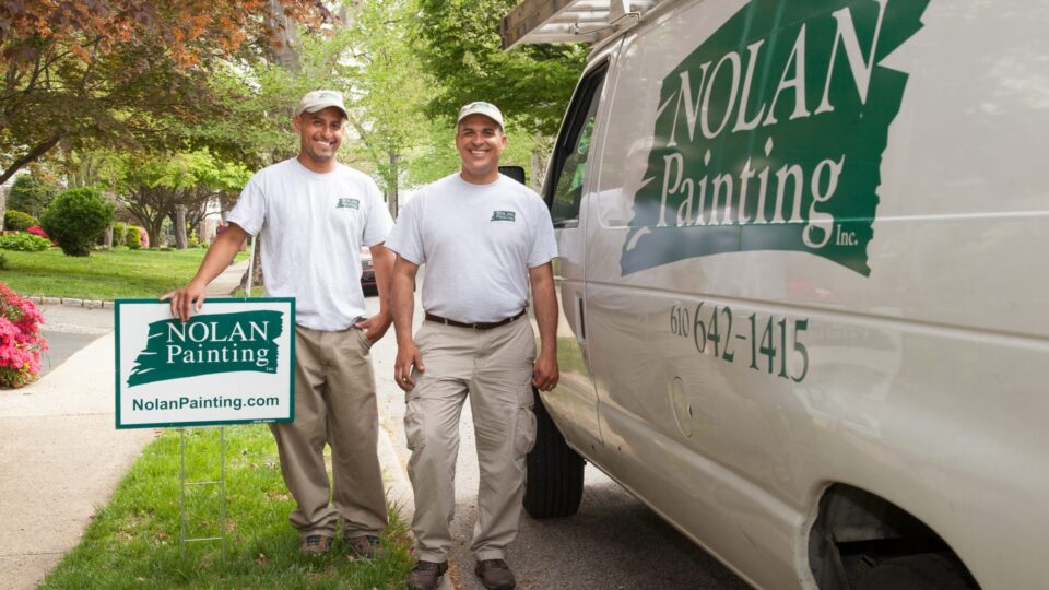 Two employees in front of Nolan Sign and Van